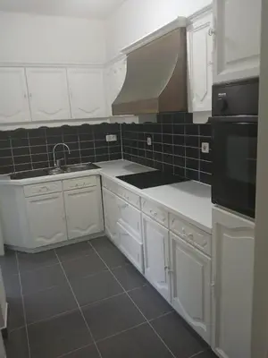 a kitchen with white cabinets and black appliances at Bloemetje in Asse