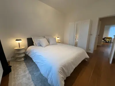 a bedroom with a large white bed with two lamps at Plein centre de Waterloo! 1 in Waterloo