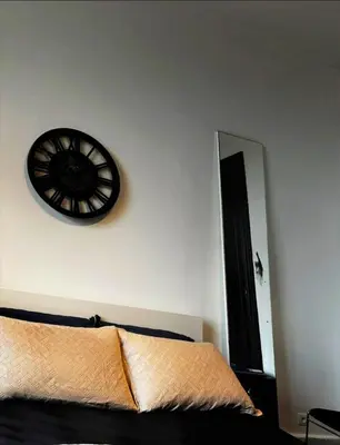 a black clock on a white wall above a bed at Room in Guest room - Charming Guest Room in Historic Brussels Mansion in Brussels