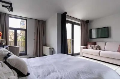 a white bedroom with a bed and a couch at Museum Suites in Antwerp