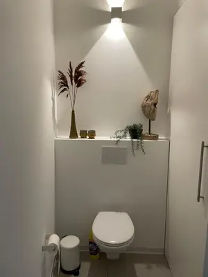 a white bathroom with a toilet and a light at Oscarsleeps in Ghent
