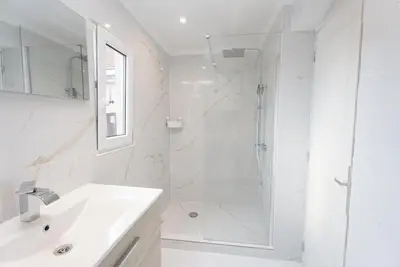 a white bathroom with a shower and a sink at Cozy apartement in the heart of Brussels in Brussels