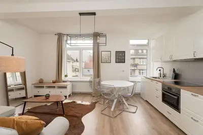 a kitchen and living room with white cabinets and a table at Cozy apartement in the heart of Brussels in Brussels