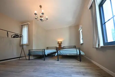 a room with two beds and a table and a chandelier at Luxe accomodatie d'einde in Beerse