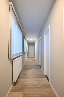 a hallway of an empty room with wooden floors and windows at Luxe accomodatie d'einde in Beerse
