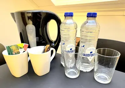 two bottles of water sitting on a counter with cups at Noah's Atomium Appartments in Brussels