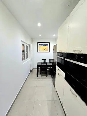a kitchen with white cabinets and a dining room with a table at Noah's Atomium Appartments in Brussels