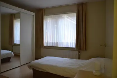 a bedroom with a bed and a large window at Lindehof Serviced Flats in Zoersel