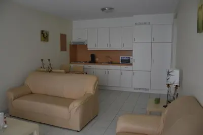 a living room with a couch and a kitchen at Lindehof Serviced Flats in Zoersel