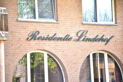 a red brick building with a sign on it at Lindehof Serviced Flats in Zoersel