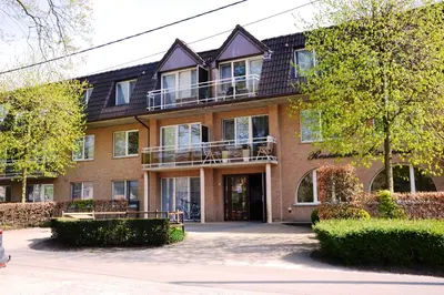 a large brick building with a balcony in front of it at Lindehof Serviced Flats in Zoersel
