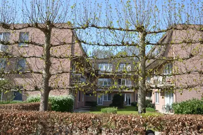 a large brick house with trees in front of it at Lindehof Serviced Flats in Zoersel