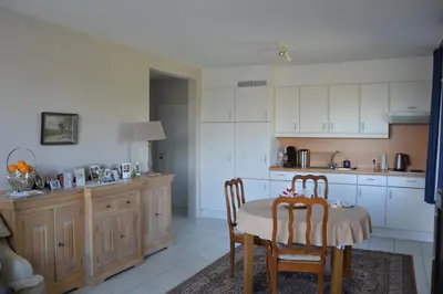 a kitchen with a table and chairs and a kitchen with white cabinets at Lindehof Serviced Flats in Zoersel