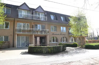 a large brick building with a balcony on it at Lindehof Serviced Flats in Zoersel