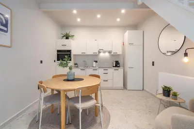 a kitchen with white cabinets and a wooden table and chairs at Gezellig, knusse en gerenoveerde rijwoning 4p in Ghent