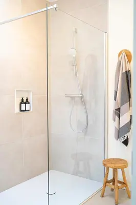 a glass shower door in a bathroom with a stool at Studio Herman met buitenterras in Kapellenbos, bij de Kalmthoutse Heide in Kapellen