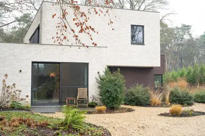 a house with a window and a chair in a yard at Studio Herman met buitenterras in Kapellenbos, bij de Kalmthoutse Heide in Kapellen