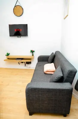 a gray couch in a living room with a clock on the wall at YabaMuandaz Apparts de Standing & Confort in Brussels