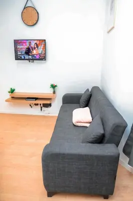 a gray couch in a living room with a clock on the wall at YabaMuandaz Apparts de Standing & Confort in Brussels