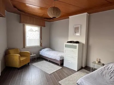 a bedroom with a bed and a chair and a window at Centrally located house for six in Rumst