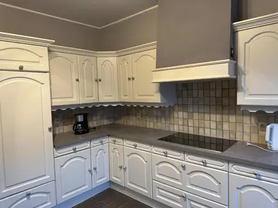 a white kitchen with white cabinets and gray counters at Centrally located house for six in Rumst