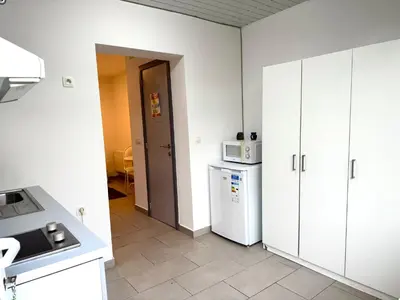 a kitchen with white cabinets and a white refrigerator at Appartement cosy à Bruxelles métro Vandervelde in Brussels