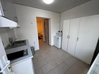 a kitchen with white cabinets and a tile floor at Appartement cosy à Bruxelles métro Vandervelde in Brussels