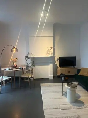 a living room with a table and a television at Bloss III Zonnige studio met dakterras in Ghent