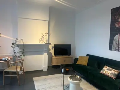a living room with a green couch and a tv at Bloss III Zonnige studio met dakterras in Ghent