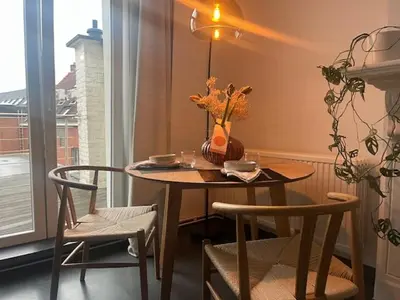a table with chairs and a vase with flowers on it at Bloss III Zonnige studio met dakterras in Ghent