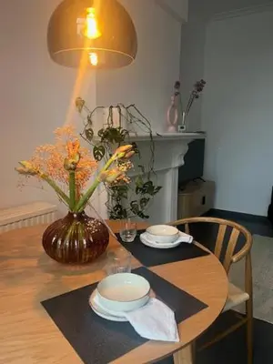 a dining room table with a vase of flowers on it at Bloss III Zonnige studio met dakterras in Ghent