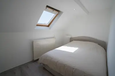 a bedroom with a white bed with a window at Cosy duplex in Brussels in Brussels