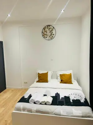 a bed in a room with a clock on the wall at Apparts de standing Bruxelles Brady Muandaz in Brussels