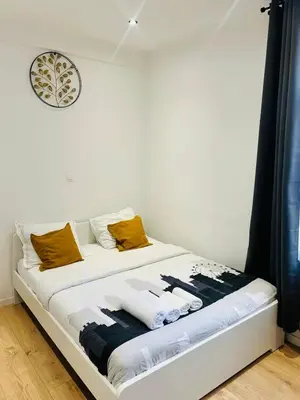 a bed in a room with a clock on the wall at Apparts de standing Bruxelles Brady Muandaz in Brussels