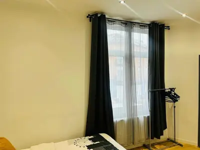 a bedroom with a window with black curtains at Apparts de standing Bruxelles Brady Muandaz in Brussels
