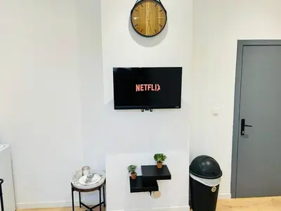 a tv on a wall with a clock on a wall at Apparts de standing Bruxelles Brady Muandaz in Brussels