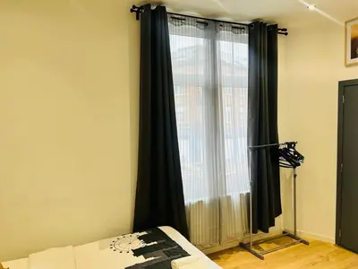 a bedroom with a large window with black curtains at Apparts de standing Bruxelles Brady Muandaz in Brussels