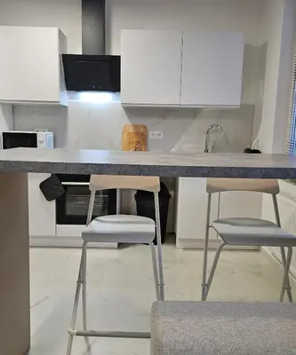 a kitchen with two stools and a counter with white cabinets at Brussels apartment with terrace 1 in Brussels