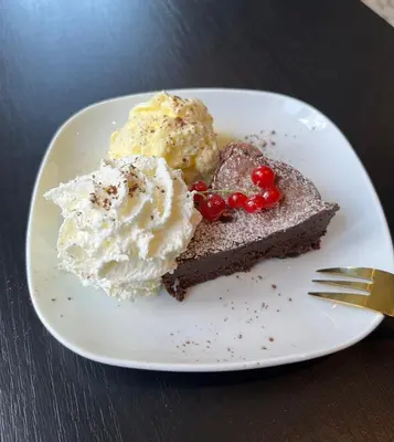a white plate with a piece of chocolate cake and ice cream at B&B Het Routehuis in Hulshout