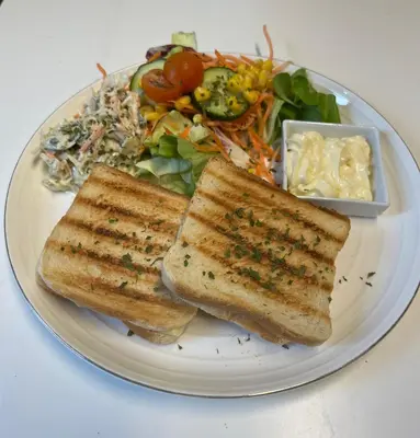 a white plate with two pieces of toast and a salad at B&B Het Routehuis in Hulshout