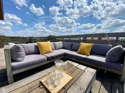 a blue couch sitting on a deck with a table at Appartement 2 chambres avec rooftop suspendu au Cimetière d'Ixelles in Brussels