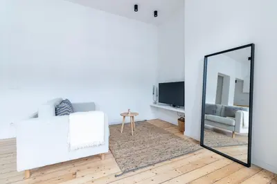 a living room with a mirror and a white couch at Sleek City Stays - Urban Elegance in the Heart of Ghent in Ghent