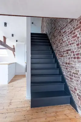 a brick wall and staircase in a room with wooden floors at Sleek City Stays - Urban Elegance in the Heart of Ghent in Ghent