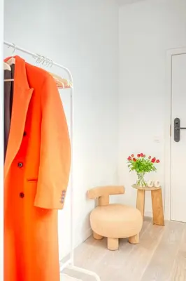 an orange coat on a rack next to a chair at 2-BR Getaway with MAS view in Antwerp