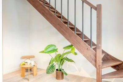 a wooden staircase in a living room with a potted plant at 2-BR Getaway with MAS view in Antwerp