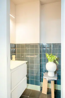 a bathroom with a sink and a vase with a plant on a stool at 2-BR Getaway with MAS view in Antwerp