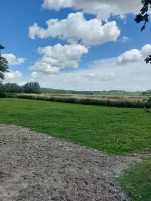 a field of grass with a blue sky and clouds at Huis-Chalet aan Puyenbroeck in Wachtebeke