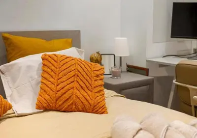 a bed with an orange pillow on top of it at 2BR apartment at new Zuidpark in Antwerp