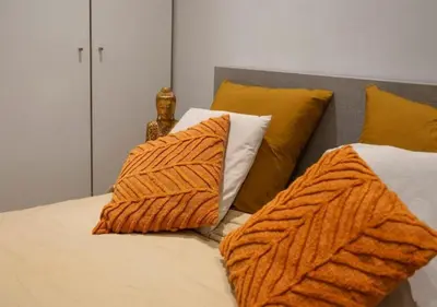 a bed with orange and white pillows on it at 2BR apartment at new Zuidpark in Antwerp