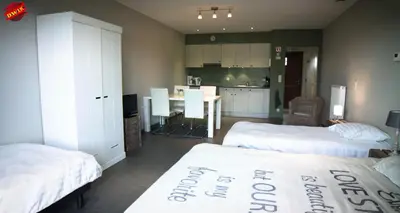 a bedroom with two beds and a kitchen with a table at Vakantiehoeve Berckelaer in Sint-Gillis-Waas